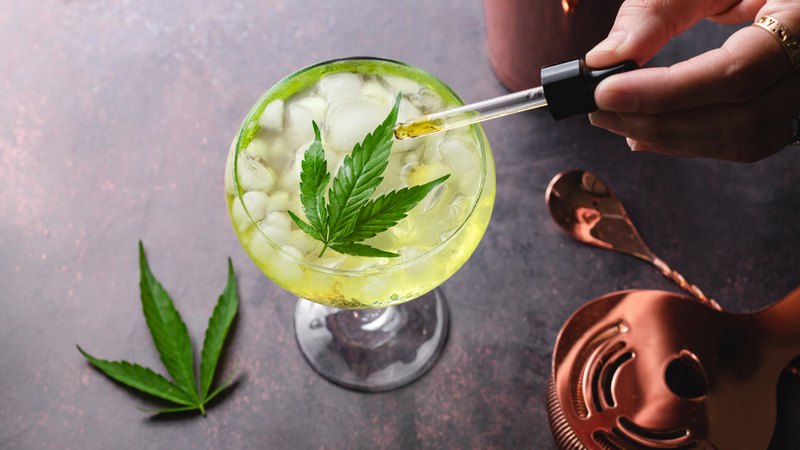 CBD oil and alcohol are used together in this margarita on the rocks with a pot leaf on top.